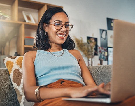 Woman smiling while working on laptop at home