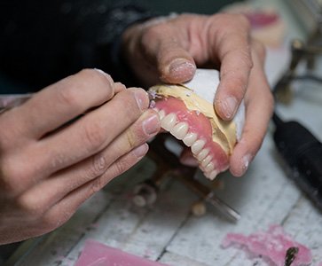 Hands carving wax gumline of dentures
