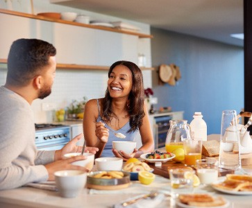 Couple smiling at each other while eating in kitchen