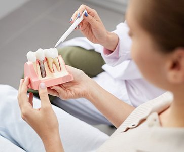 a patient holding a plastic model of a dental implant