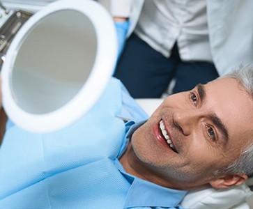 a patient checking his new dental implants with a mirror