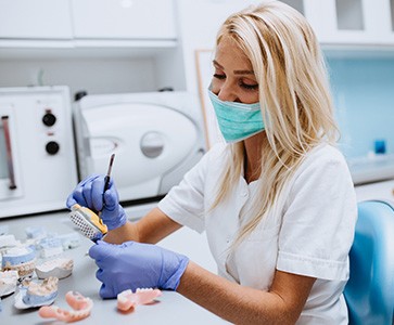 lab tech customizing sets of dentures