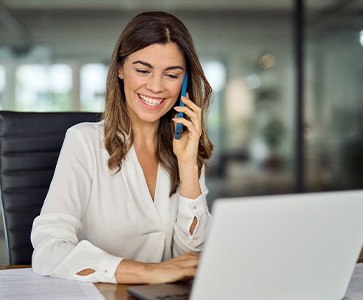 Woman smiling while talking on phone in office