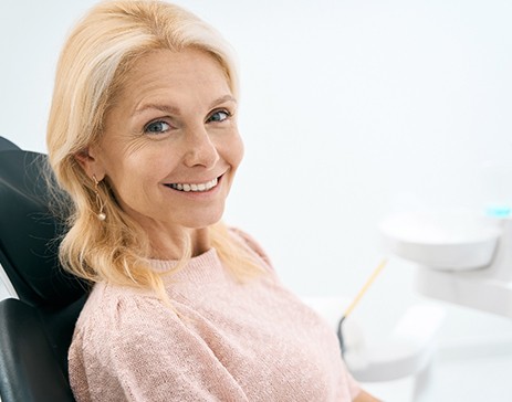 An older, smiling woman sitting in a dental clinic