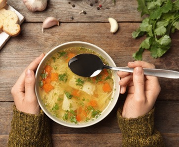 An overhead view of chicken soup at a table