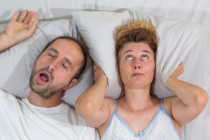 woman covering ears from snoring