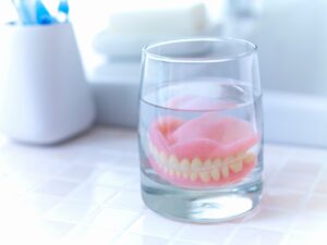 Dentures sitting in glass of water.